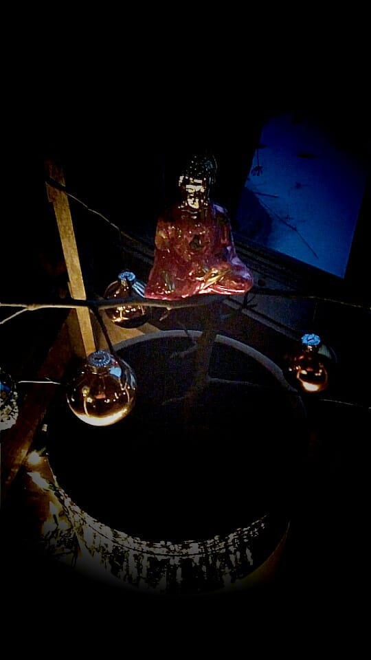 A glass Buddha sits in light on the night of remembering Buddha's enlightenment