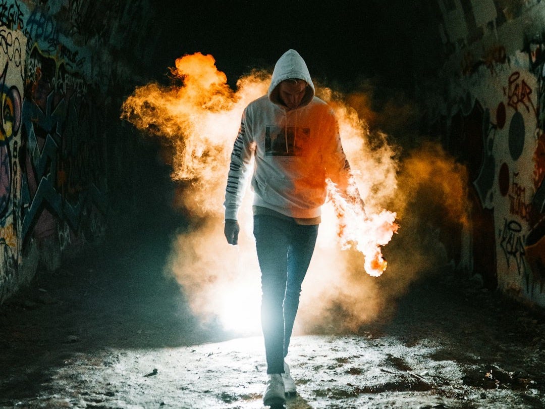 woman in orange jacket and blue denim jeans standing on tunnel