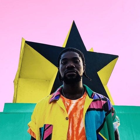 A young Ghanaian man in a colorful jacket standing in front of a black star against a pink background