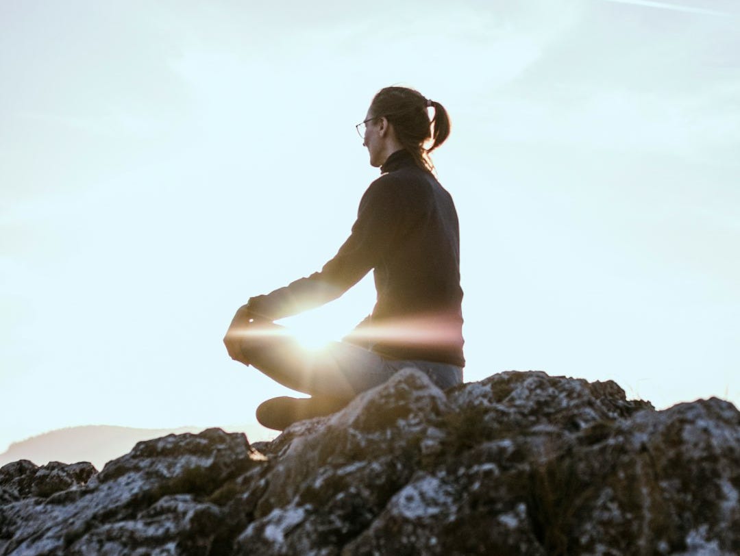 person sitting on rock formation during daytime