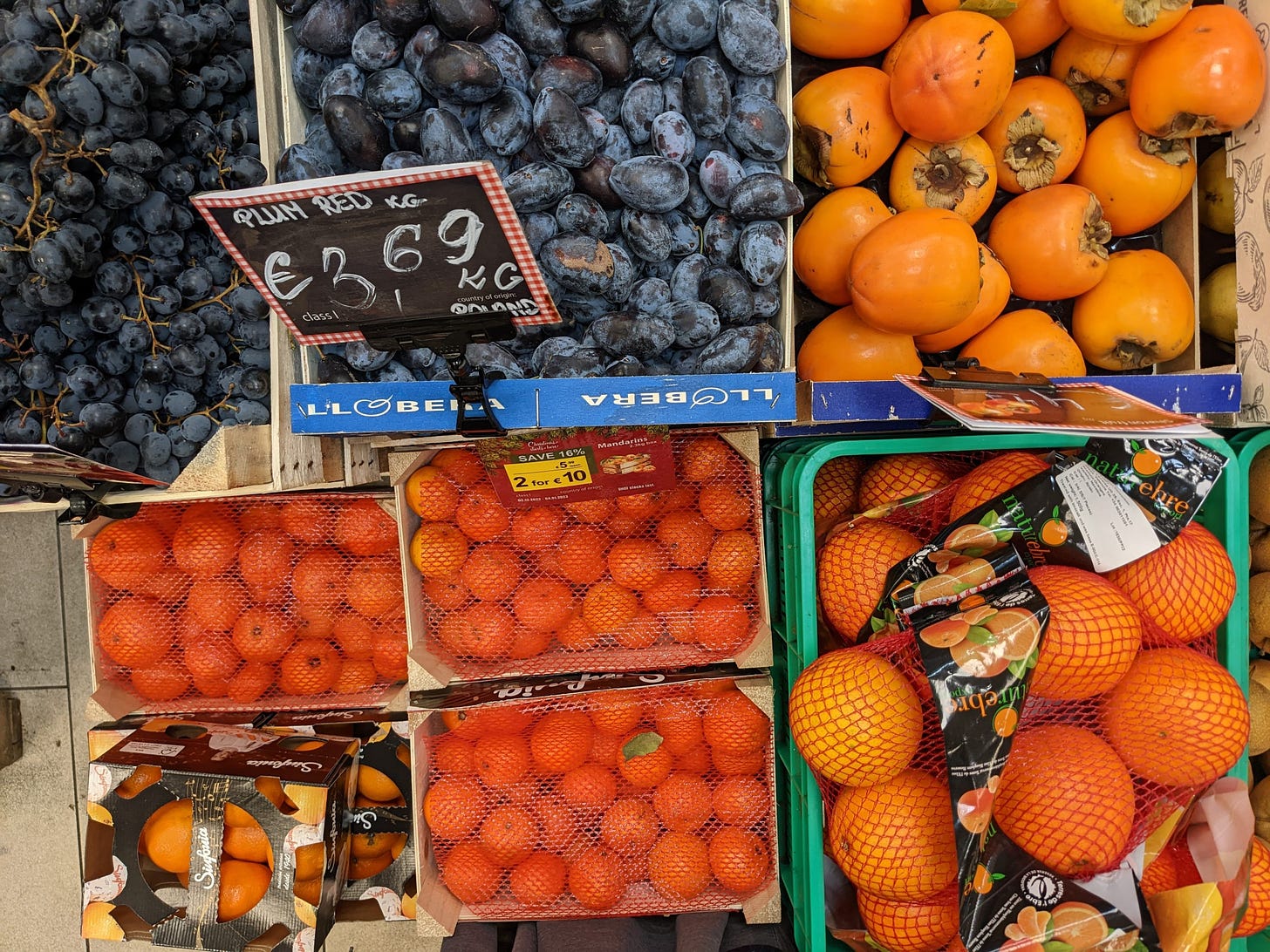 plums, oranges, and persimmons in crates