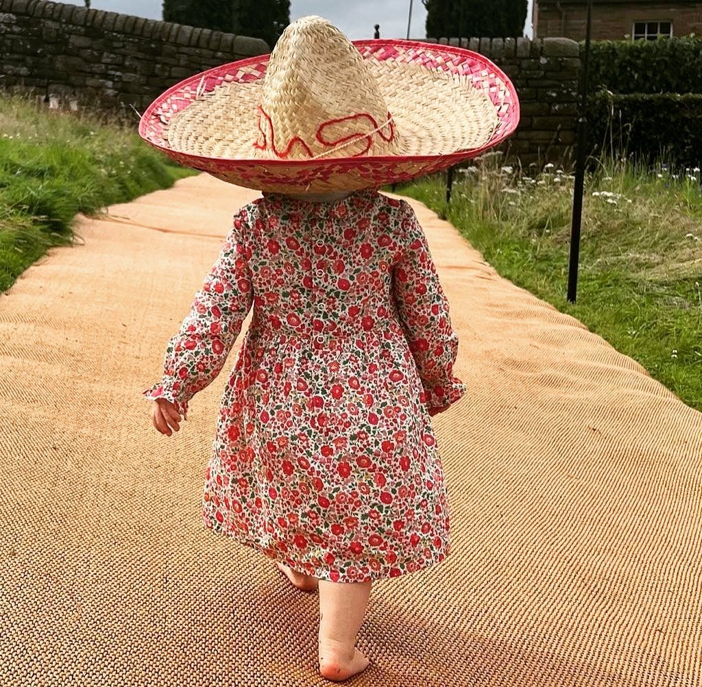 Edoardo's daughter from behind in sombrero and floral print dress