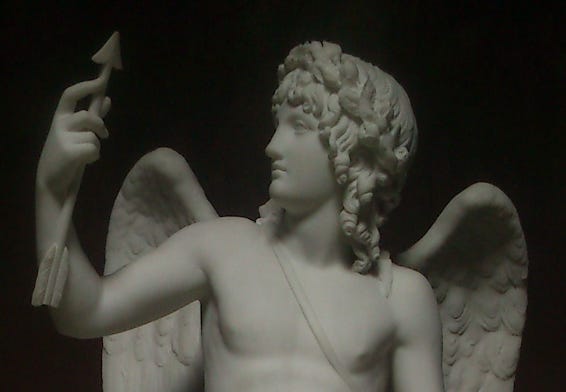 Image Description: a statue of a winged Cupid staring at an arrow in his hand