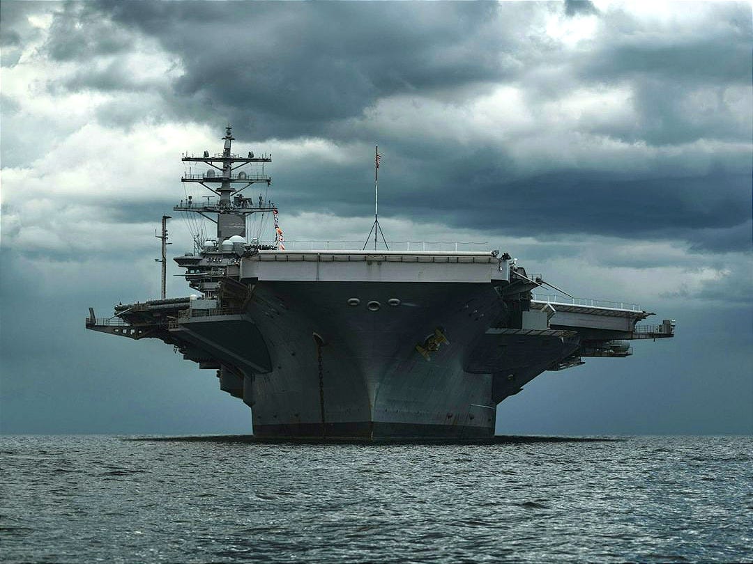 a large aircraft carrier floating on top of a body of water a large aircraft carrier floating on top of a body of water