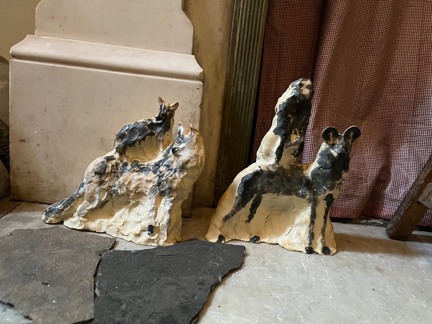 Two animal sculptures: one with a poodle sitting on top of a wolf, and the other with a monkey sitting on top of a hyena.