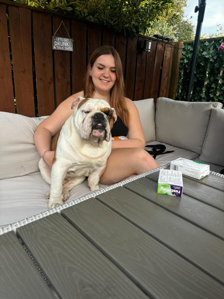 Young woman sitting on patio furniture with her bulldog.