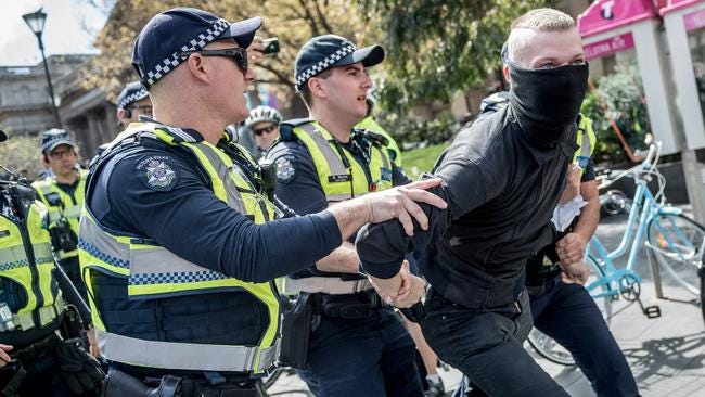 A man is taken into custody after wearing a mask at the Melbourne rally. Picture: Jake Nowakowski.