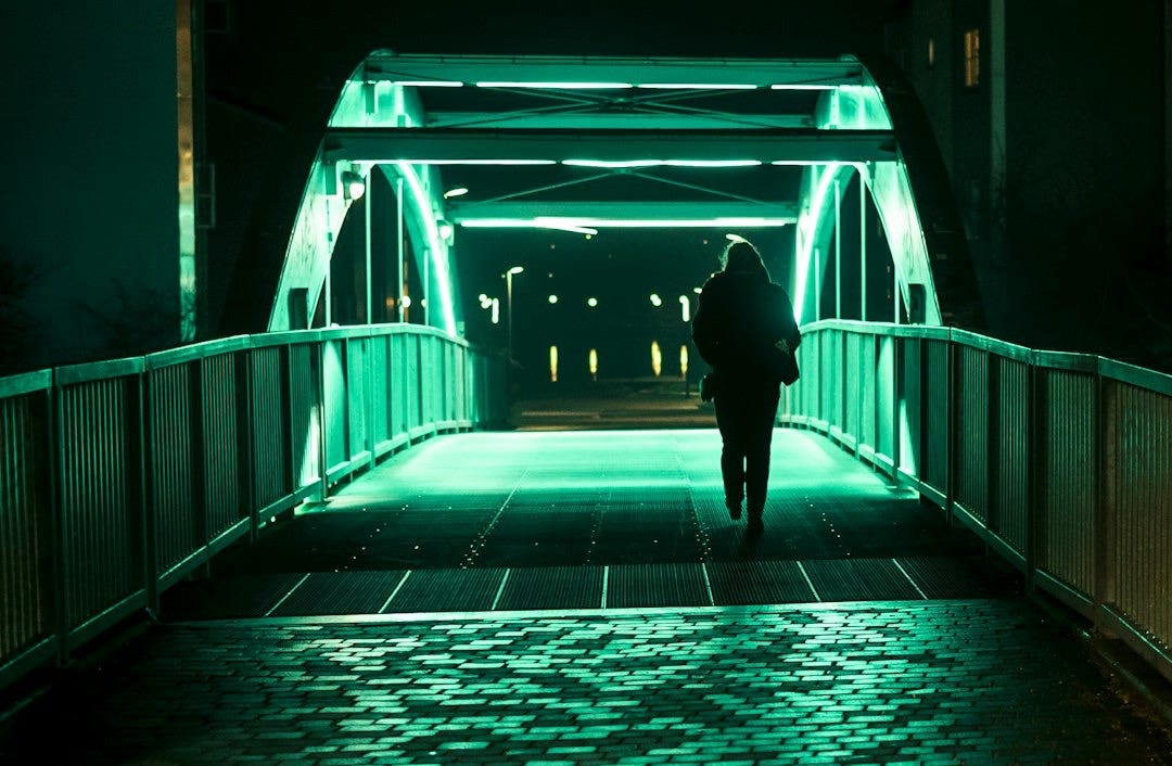 person passing alone on bridge during nighttime