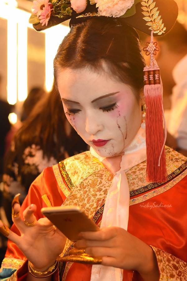 Woman in an elaborate Chinese costume, texting on a smartphone