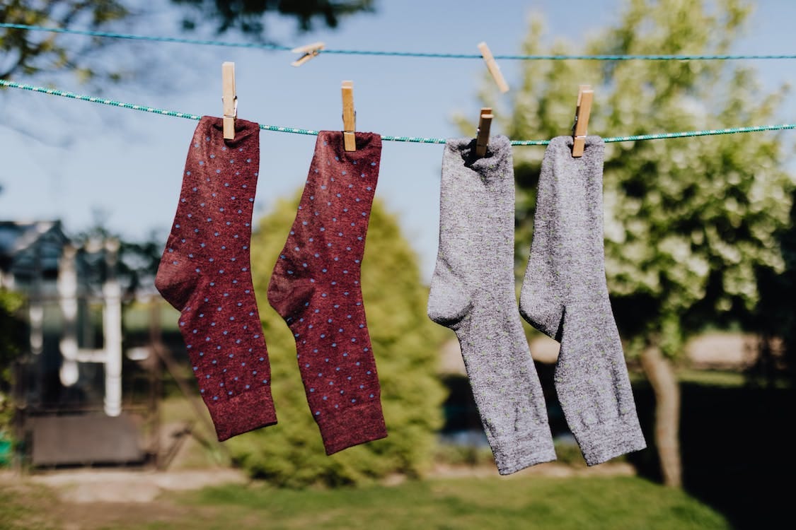 Free Soft focus of washed multicolored socks hanging on rope with clothespins outdoors on sunny summer day against natural background Stock Photo