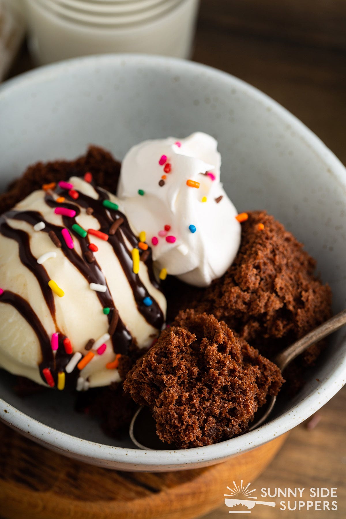 Chocolate cake in a bowl with ice cream and whipped cream.