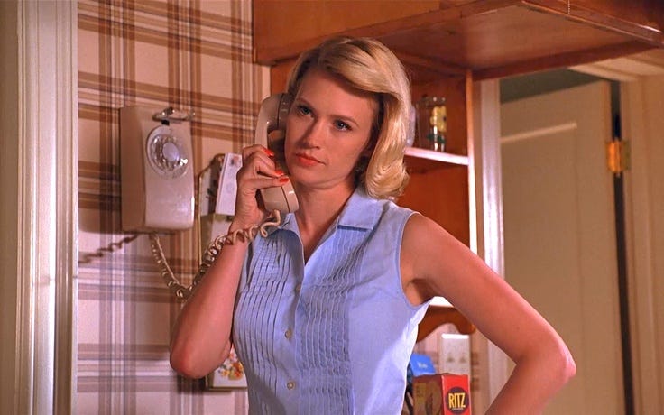 This may contain: a woman is talking on the phone while standing in front of a wall mounted telephone
