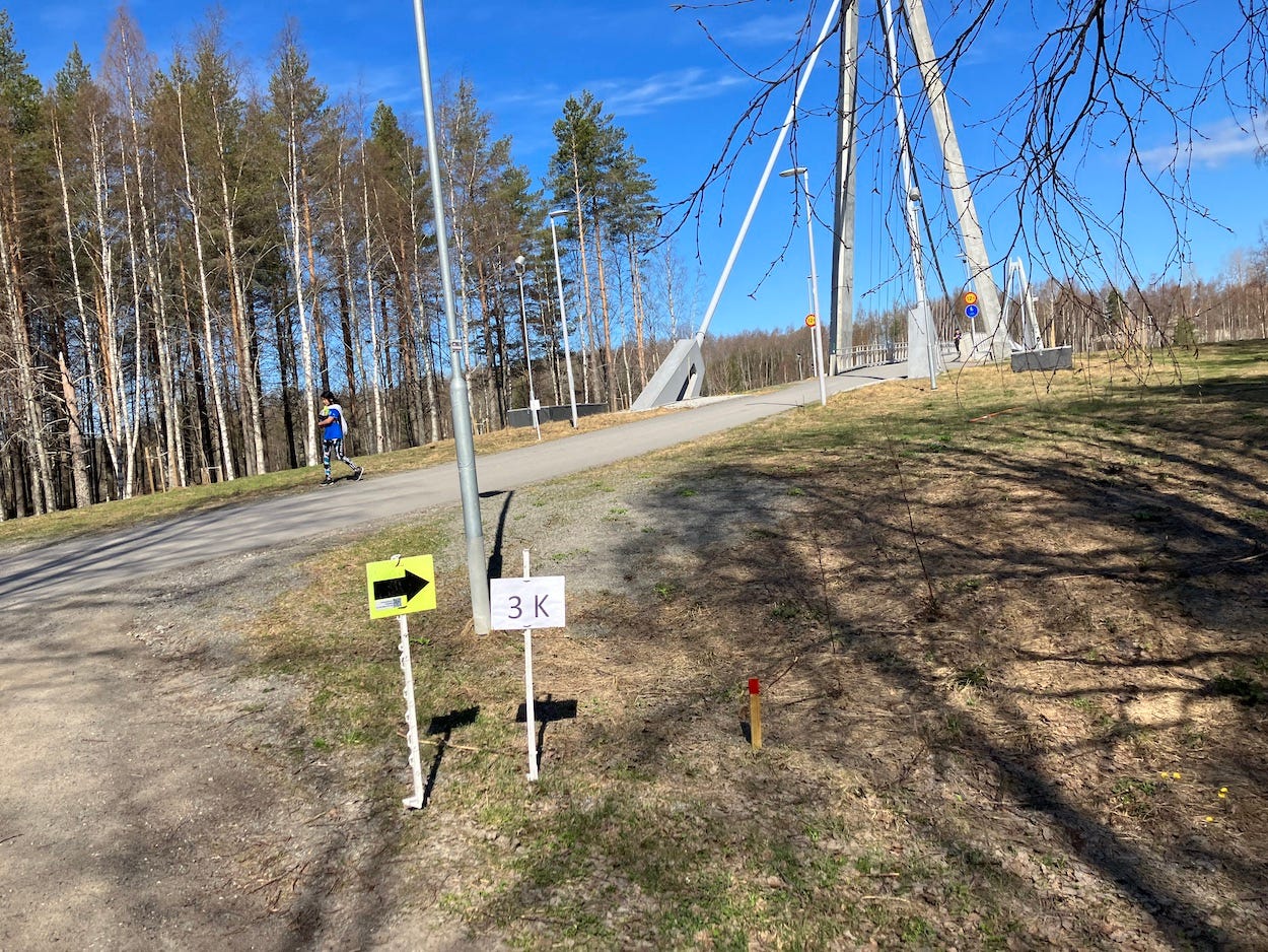 3k marker next to the bridge. Grass and thin trees border the path