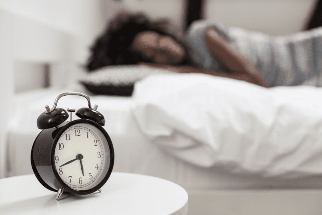 young woman sleeping in bed with alarm clock on nightstand