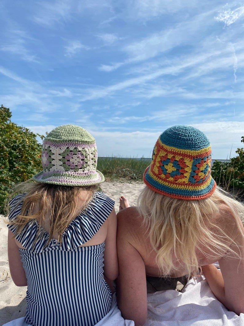 Mummy and daughter in matching granny square crocheted bucket hats on the beach