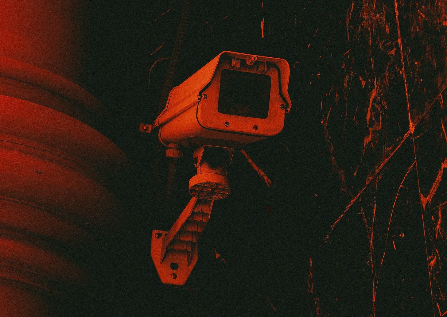 Closeup of ominous outdoor surveillance camera, black and red duotone effect.