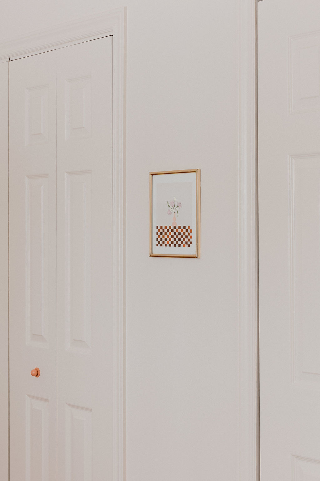 painted closet doors with pink knobs and a small art print by erica catherine