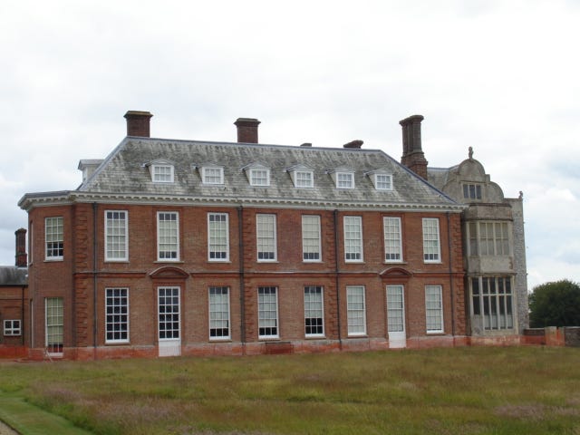 Seventeenth century English manor house in red brick with many large windows.