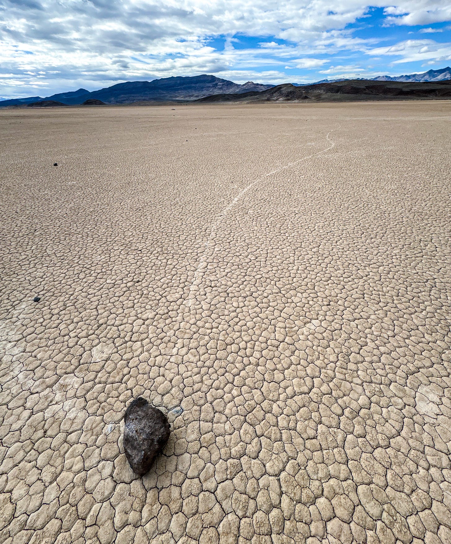 Dry lake bed with clouds and mountains in distance.