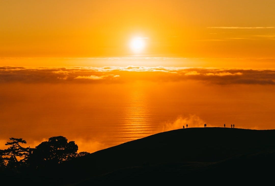 people on top of hill under white clouds golden hour photography