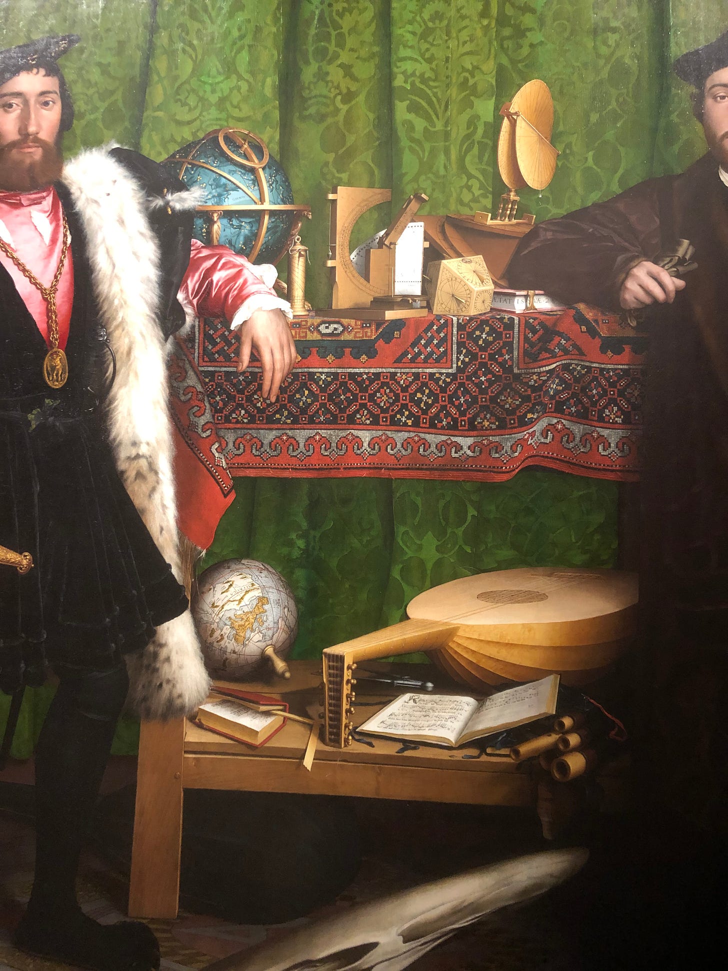 A close up of the table in the painting described above - the instruments and sheet music, globe and mathematical instruments are clearly visible. The top of the table is covered with a red and black woven carpet.