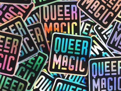 a photo of a bunch of black stickers with shiny text that says "Queer Magic"