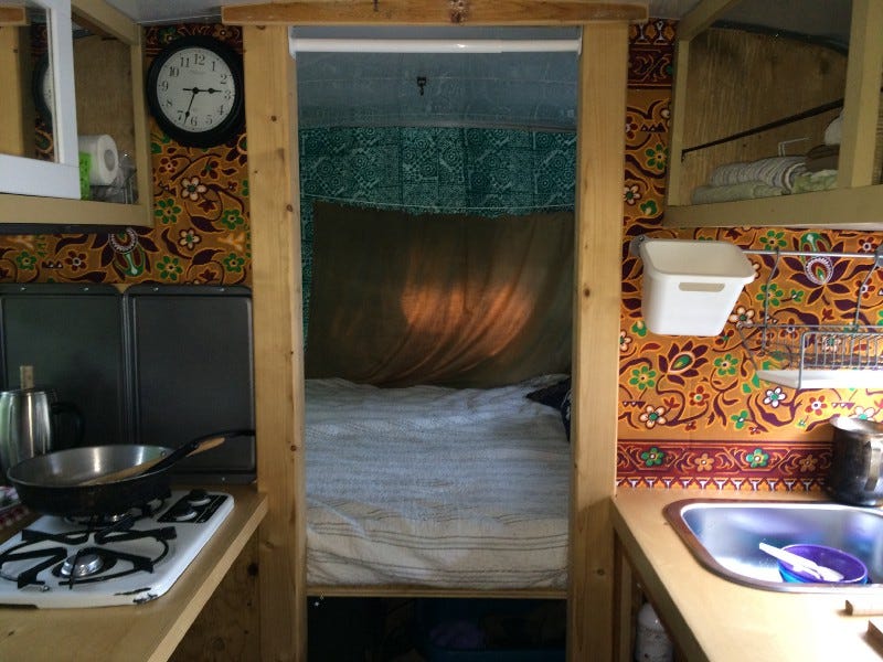 Interior of converted short school bus showing stove, bed, sink.