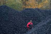 FILE - A worker walks past piles of coal at a selling point in Ostrava, Czech Republic, Nov. 11, 2022. The European Union has been at the forefront of the fight against climate change and the protection of nature for years. But it now finds itself under pressure from within to pause new environmental efforts amid fears they will hurt the economy. (AP Photo/Petr David Josek, Fie)