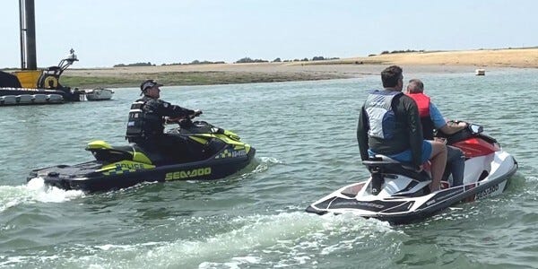 Marine Unit office on a jetski engaging with two members of the public on another jetski