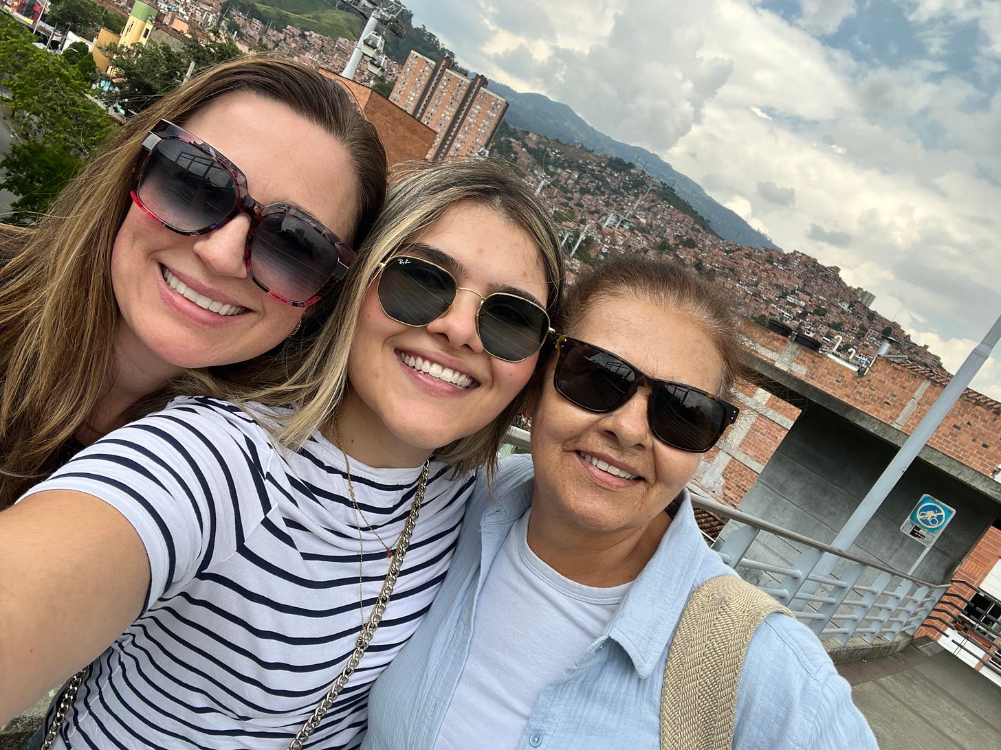 selfie of three women with Medellin settlements in the background