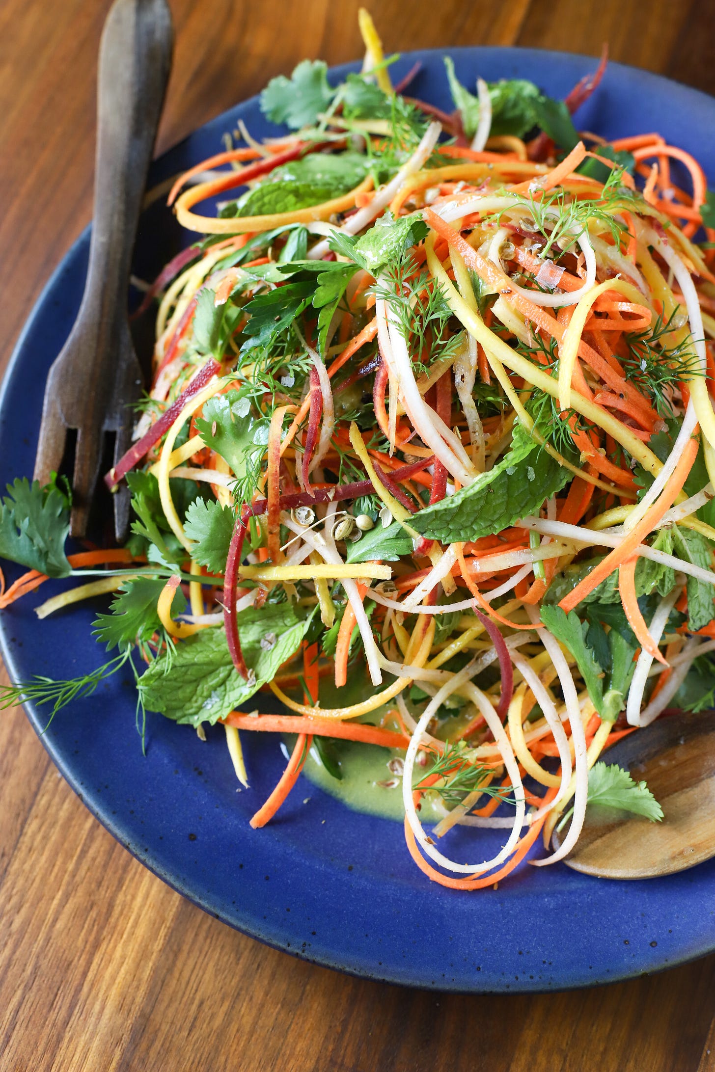 Grated carrots and herb salad on blue plate