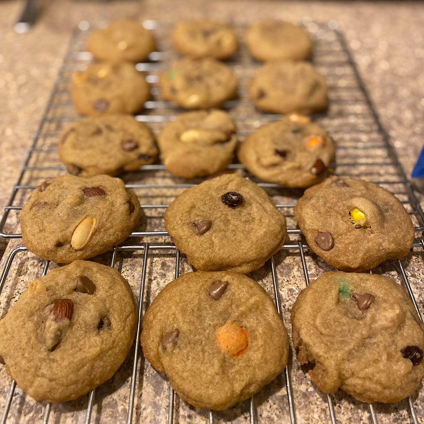 On a cooling rack, cookies with chocolate chips, M&Ms, and nuts.