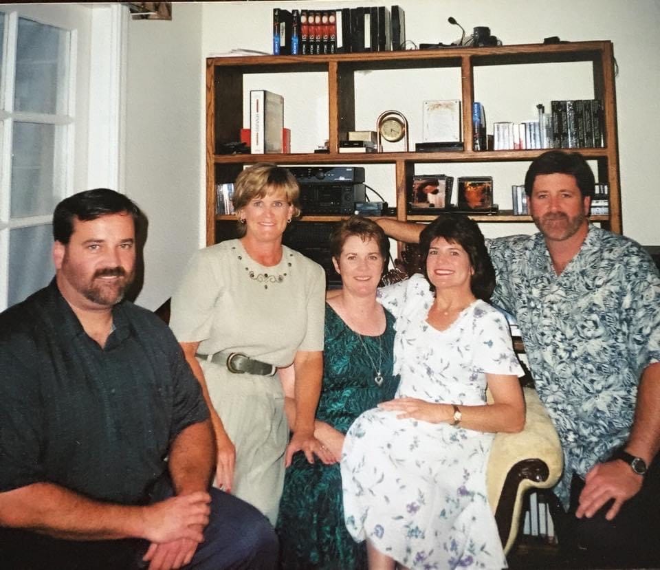 Five adult siblings—two male, three female—sitting together to have their photo taken.