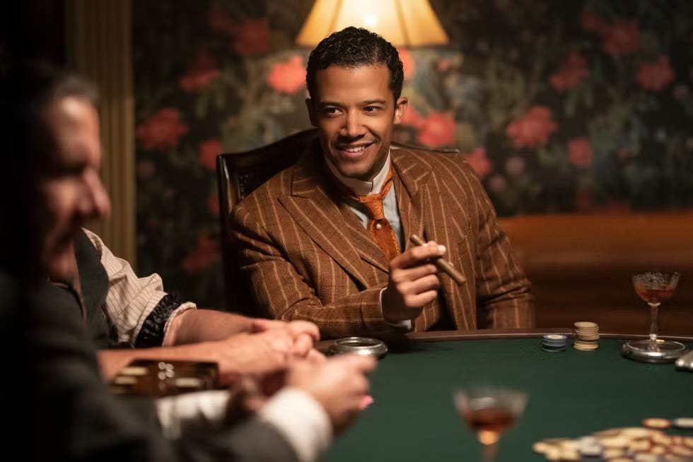 Jacob Anderson as Louis in Interview with the Vampire smoking a cigar at a card game