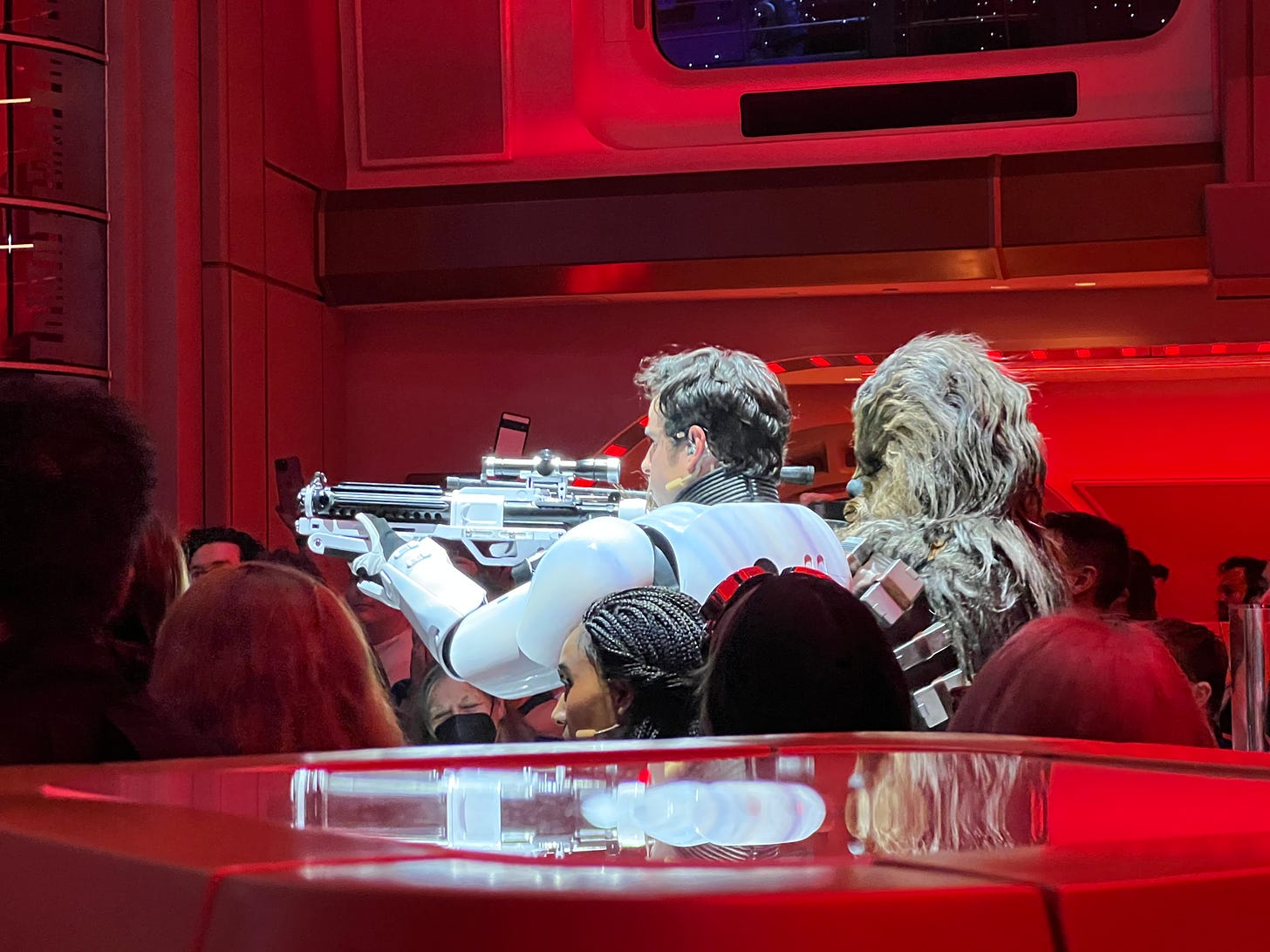 A stormtrooper with his helmet off toting a gun, next to Chewbacca