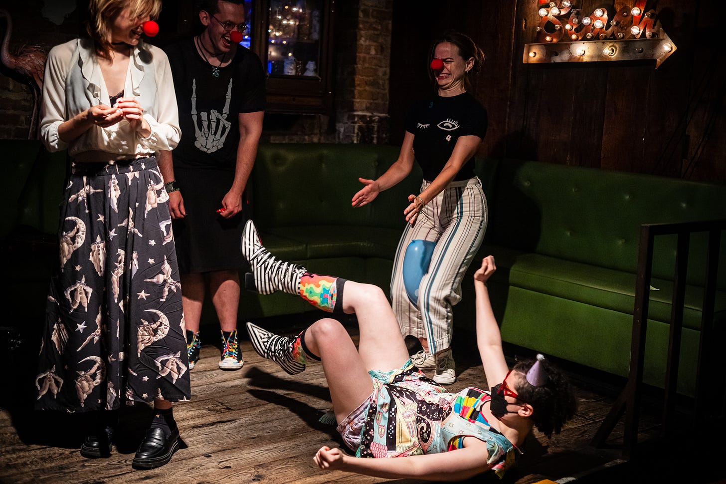 four people in red noses pop balloons with their body onstage at queers n peers variety show