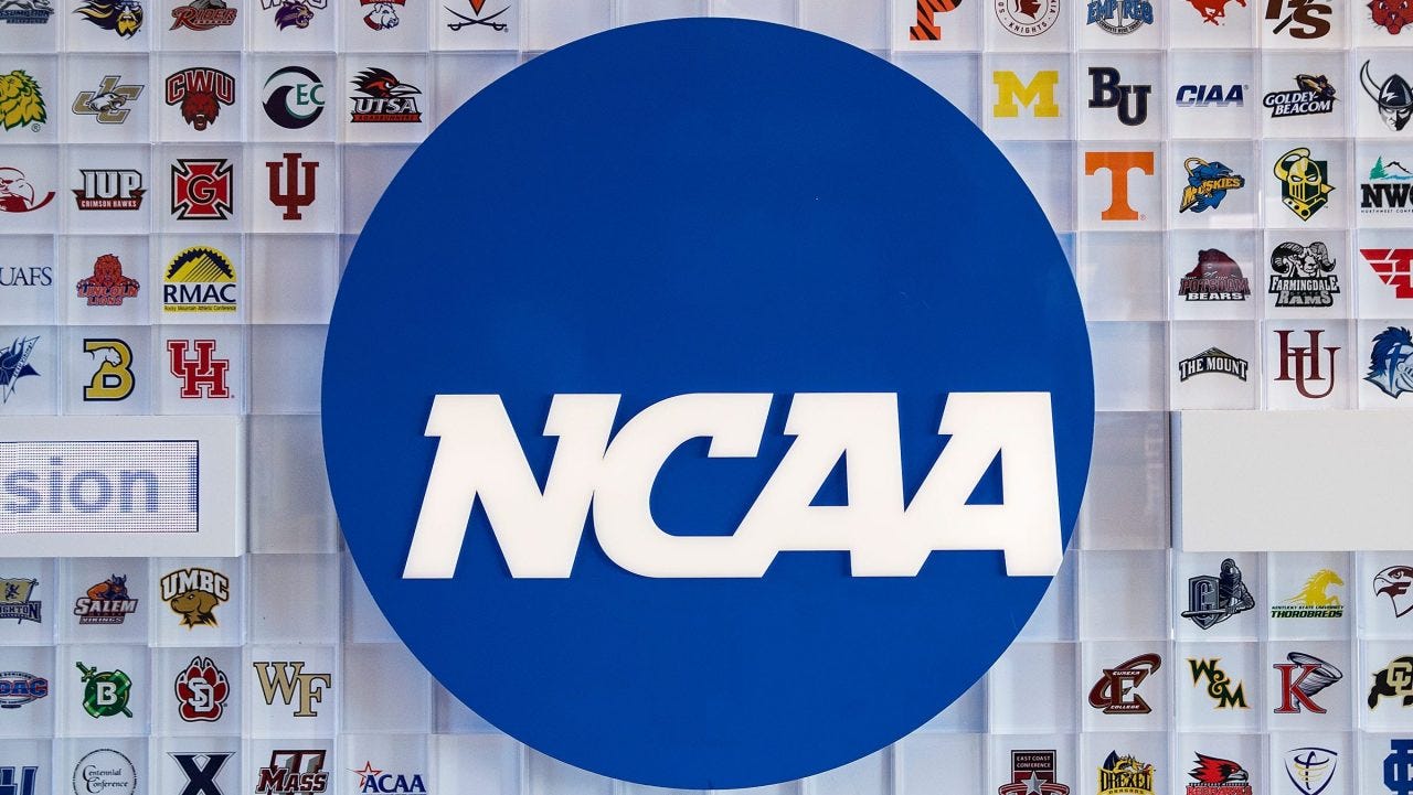 University logos cover a wall in the lobby of NCAA headquarters