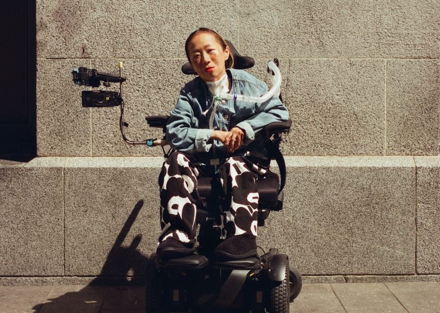 Alice Wong in her wheelchair wearing cow print pants.