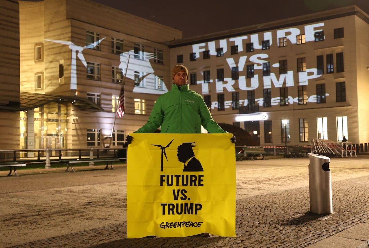 A Greenpeace environmentalist holds a banner showing a wind turbine that reads "Future vs. Trump" as the same image is projected on the facade of the U.S. Embassy to protest against the withdrawal of the United States from the Paris Agreement by newly-inaugurated U.S. President Donald Trump