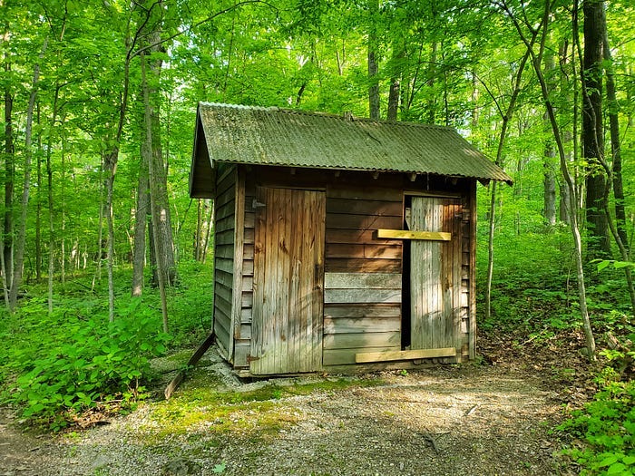 A locked up, abandoned outhouse somewhere in the state forest.