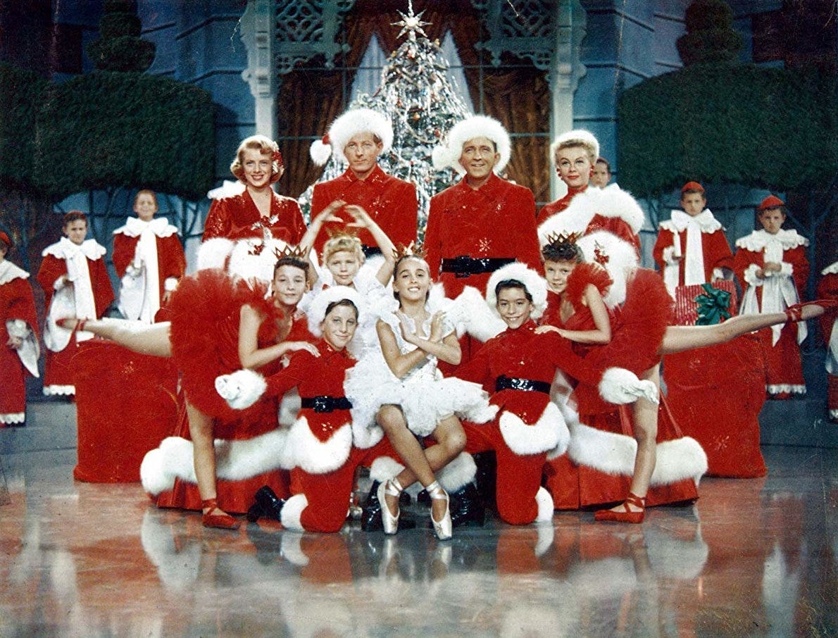 Festive scene with entire cast gathered about Christmas tree and ballerina at the center.