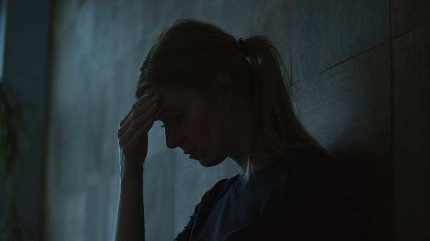 La niña se sienta en una habitación oscura y sufre un colapso mental: depresión. - foto de stock