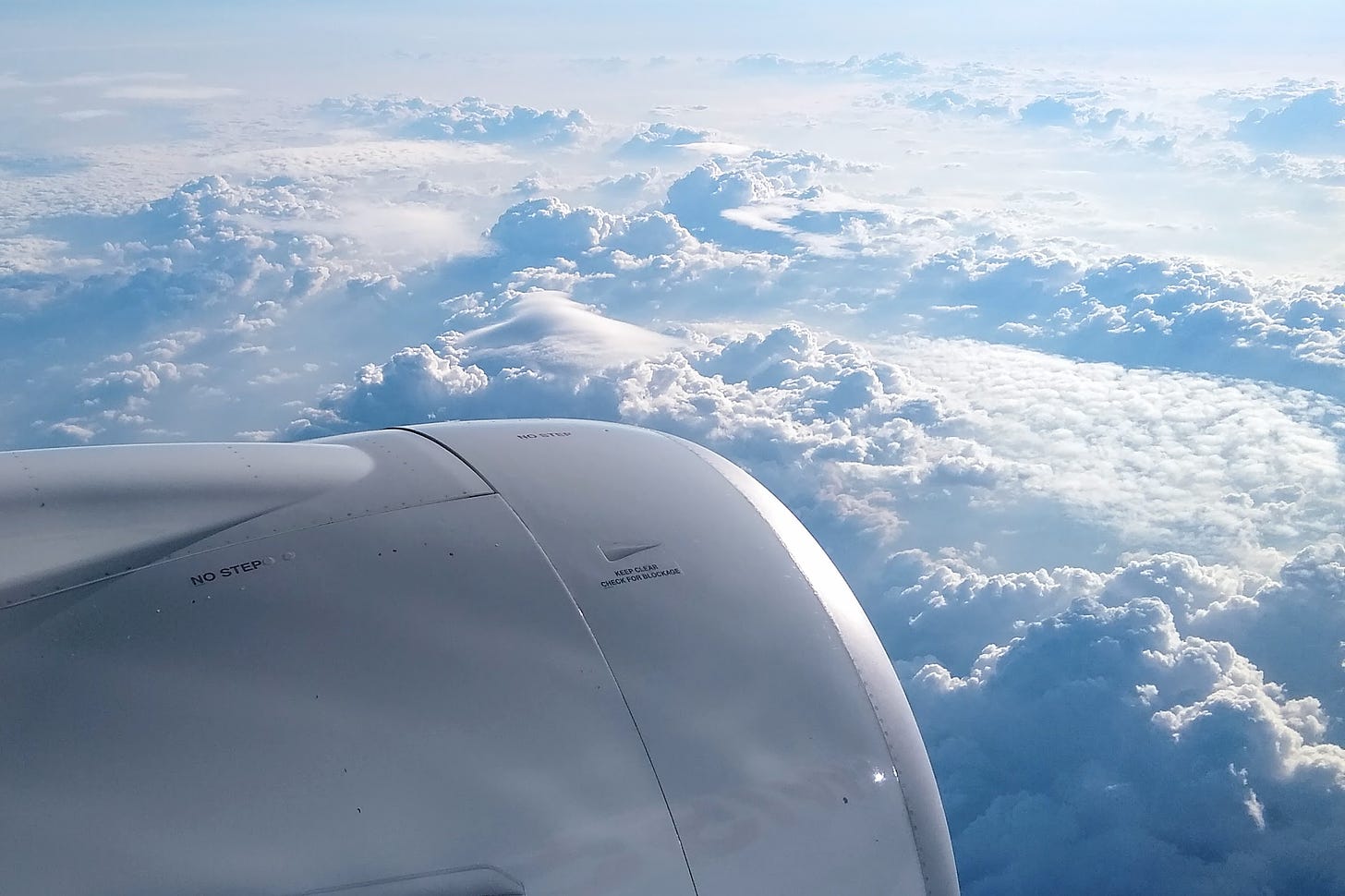 Port side view of a jet engine and cumulus clouds from a passenger airplane window