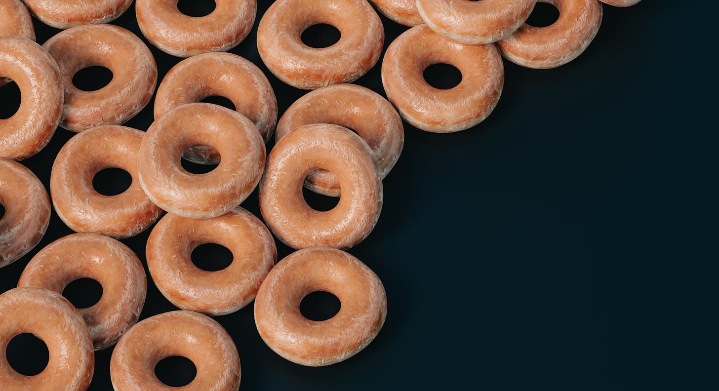 Many glazed donuts on a dark background.