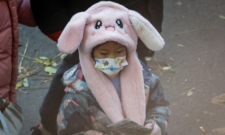 A child in Beijing wearing a face mask and a pink winter hat