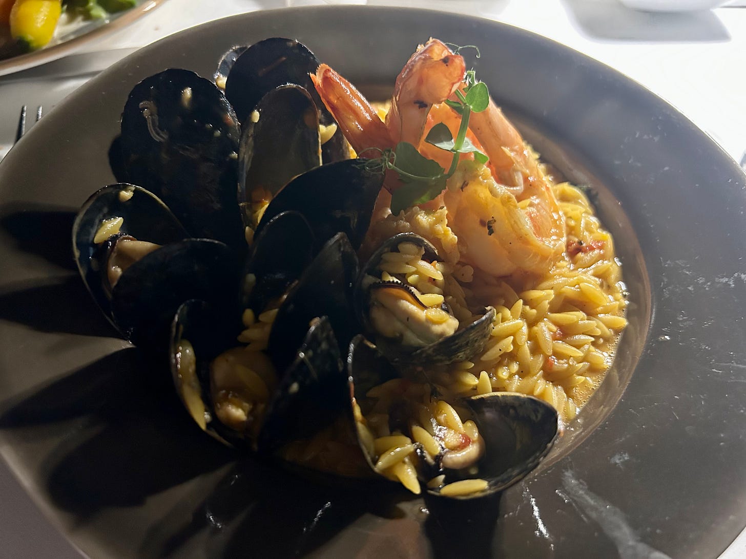 A plate of risotto, prawns and mussels.