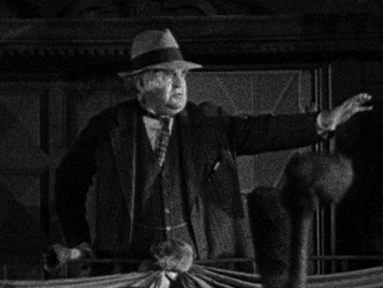 Mayor the small town in the 1931 film Frankenstein speaks from the balcony of the town hall, rallying the townspeople to take on the monster, He’s wearing a trilby