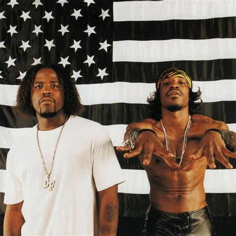 The cover of Outkast’s STANKONIA album, showing Big Boi on the left in a white t shirt, and Andre 3000 on the right, shirtless and in leather pants, his hands raised in front of him as if trying to bring someone magically back to life. Behind them, the American flag, in black & white.