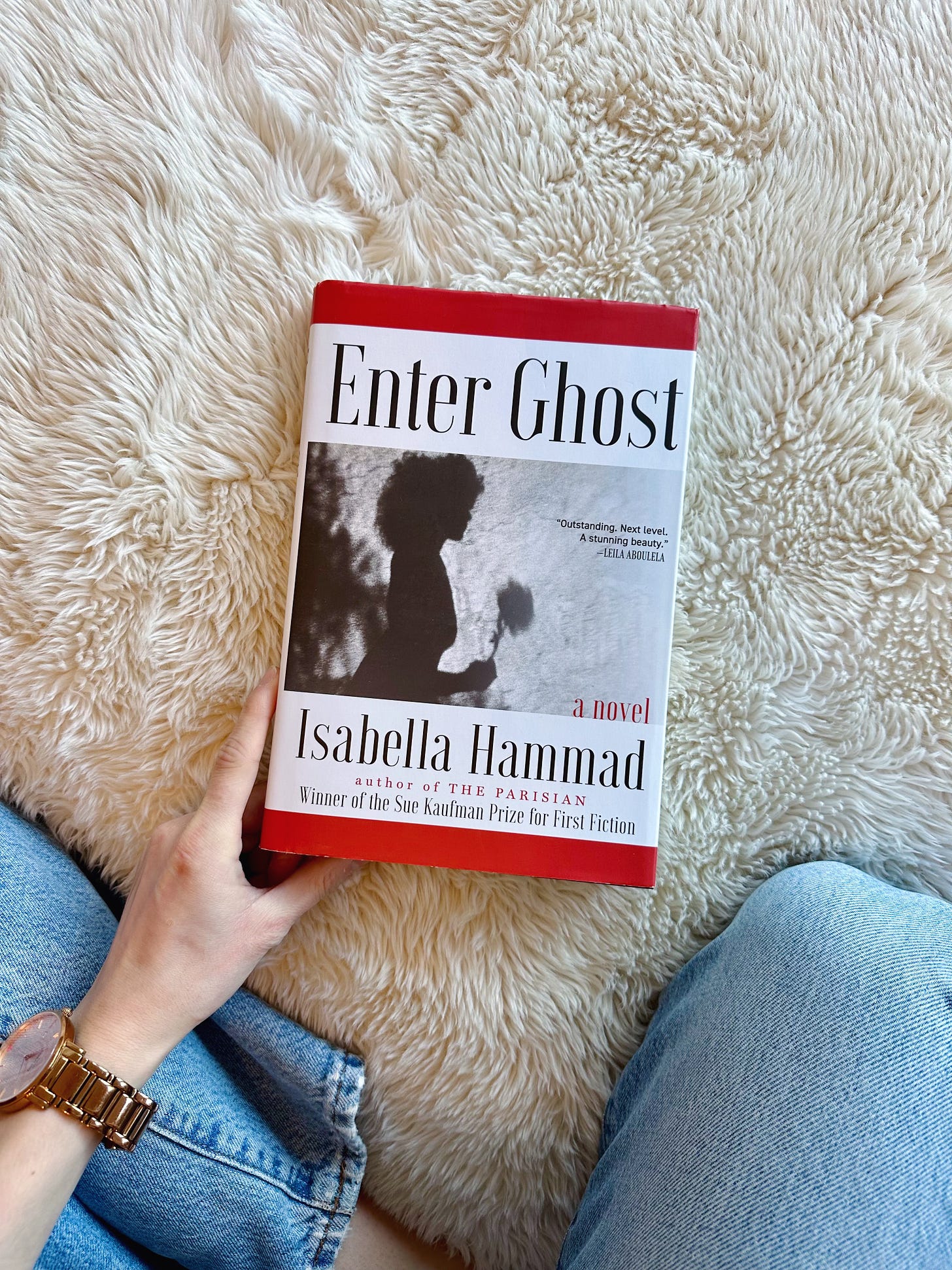 A white hand holds Enter Ghost on a white blanket