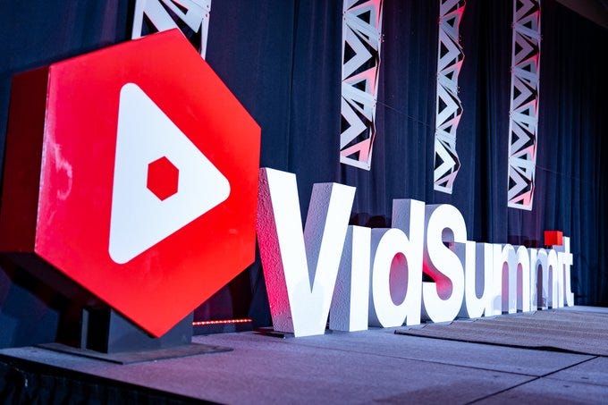 A large red and white installation on an event stage that reads VidSummit